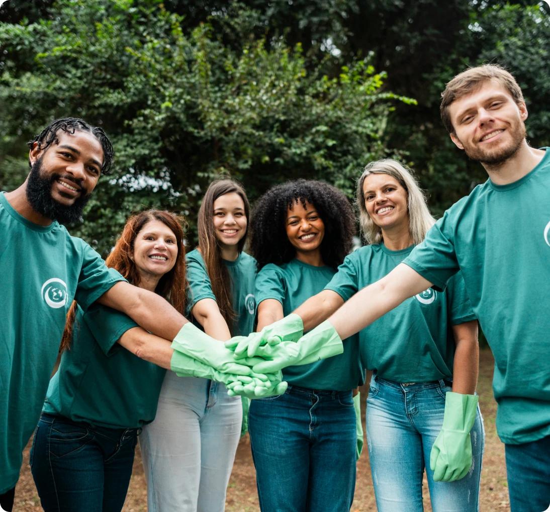 Group of volunteers joining hands outdoors